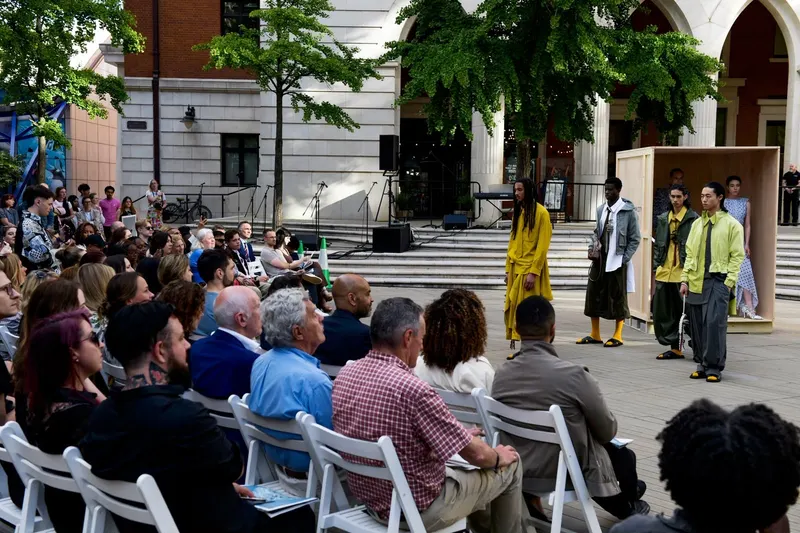 Wide view of a seated audience watching models in the distance