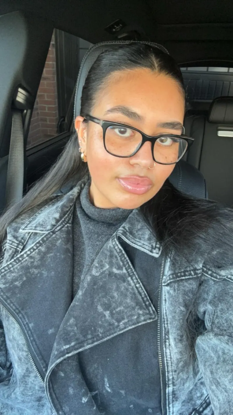 Portrait of Marnz, fashion designer, wearing glasses and a washed black denim jacket
